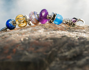 Trollbeads bracelet with blue and violet gemstones with beads in silver, gold secured with a silver clasp with an amethyst. 