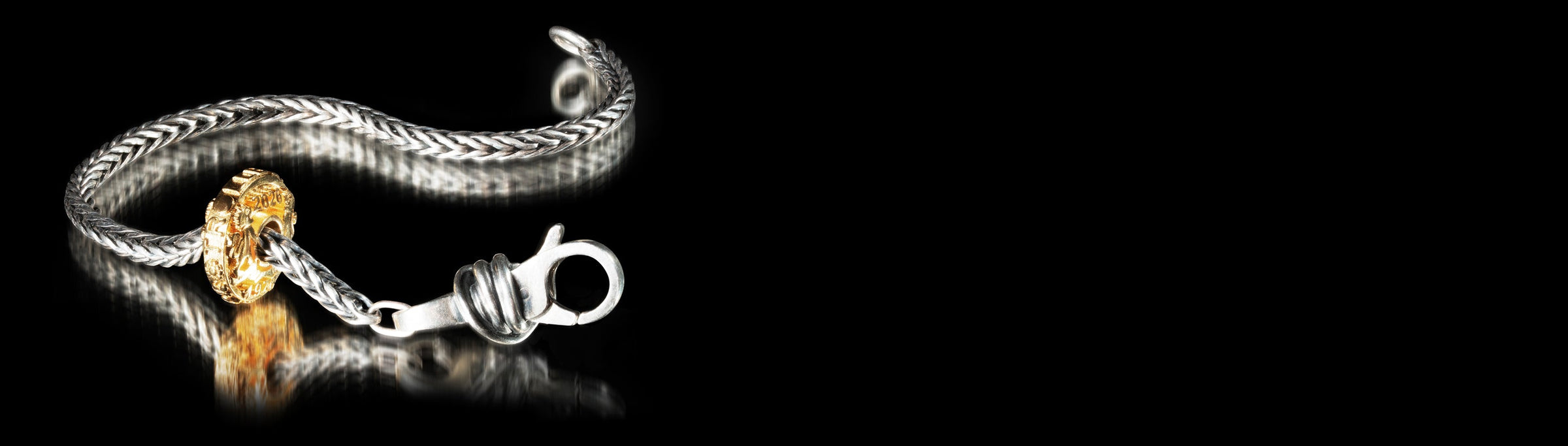 Silver bracelet with a gold-plated bead on a black background